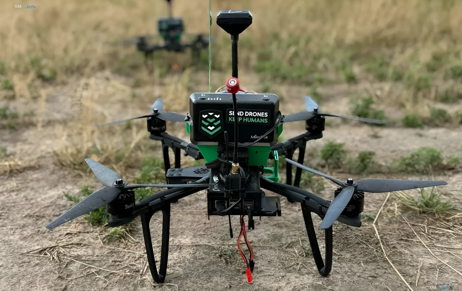 Боевой дрон с надписью 'SEND DRONES KEEP HUMANS' на поле, демонстрирующий технологии роевого управления для Пентагона
